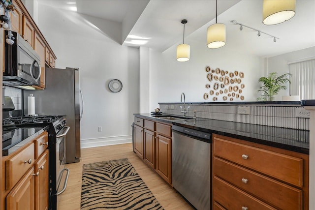 kitchen featuring appliances with stainless steel finishes, light hardwood / wood-style floors, pendant lighting, and sink