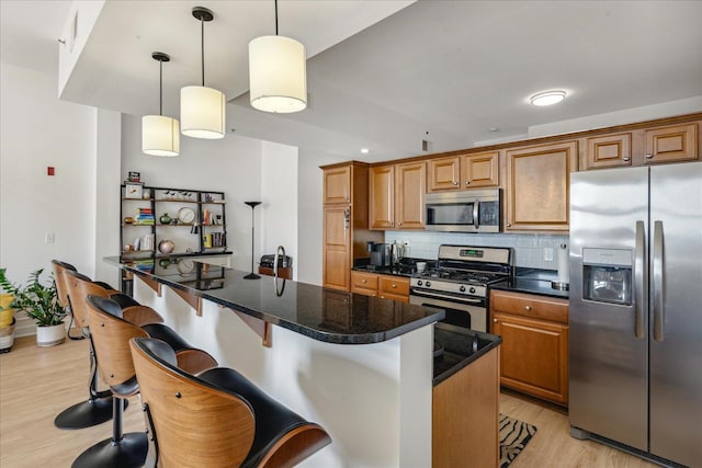 kitchen featuring a kitchen breakfast bar, light wood-type flooring, backsplash, stainless steel appliances, and a center island