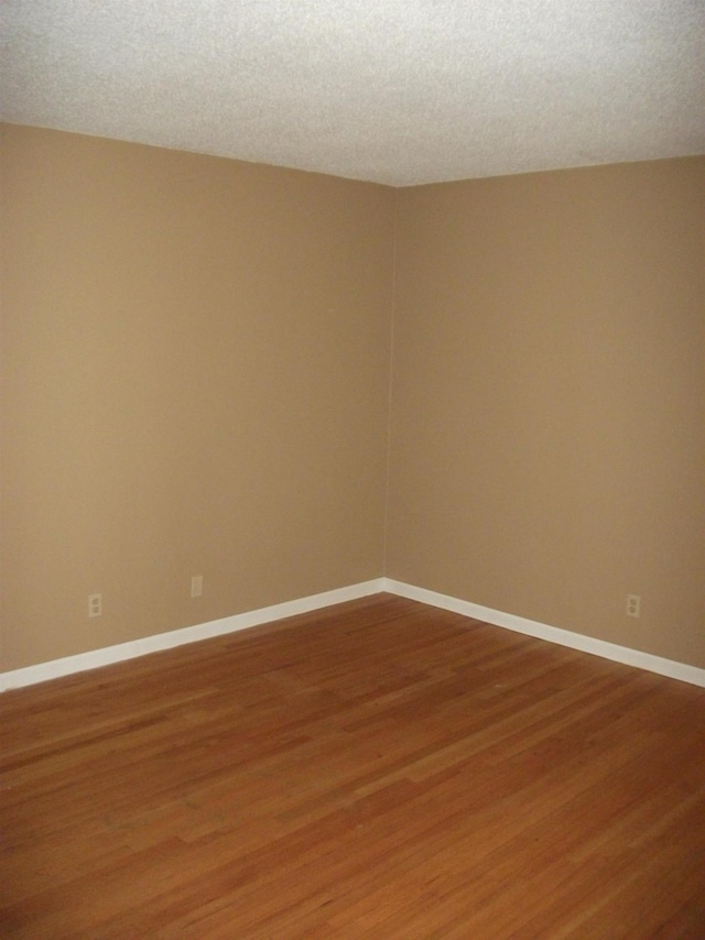 unfurnished room with wood-type flooring and a textured ceiling