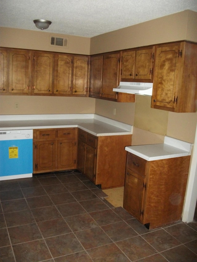 kitchen featuring dark tile patterned floors, white dishwasher, and a textured ceiling