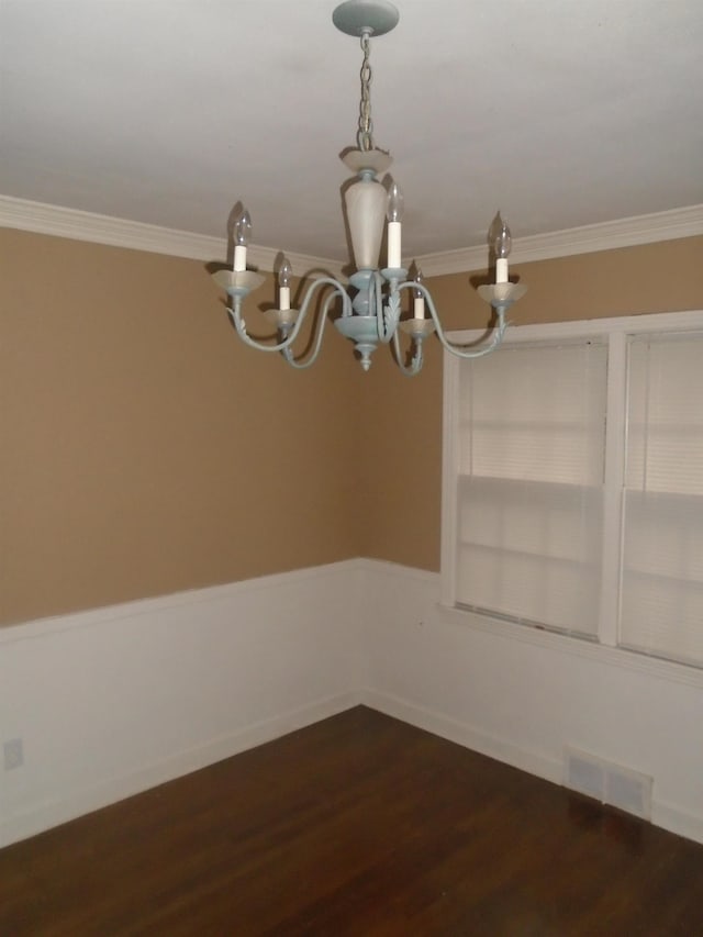 unfurnished dining area featuring ornamental molding, dark wood-type flooring, and an inviting chandelier