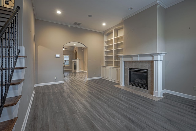 unfurnished living room featuring a tile fireplace, dark hardwood / wood-style flooring, and crown molding