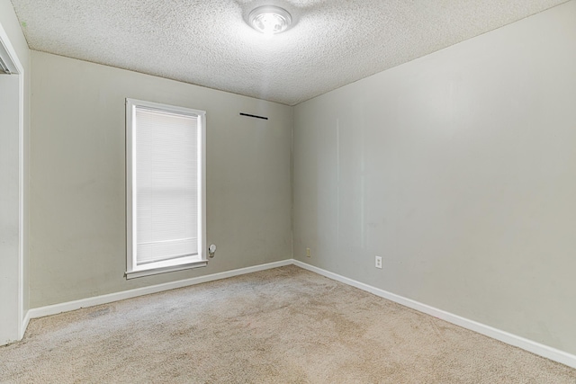 empty room with light carpet and a textured ceiling