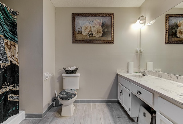 bathroom with a textured ceiling, vanity, toilet, and hardwood / wood-style floors