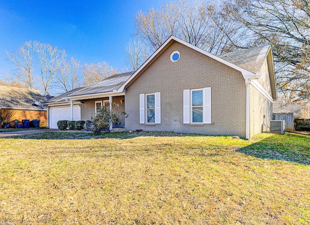 view of front of home featuring a front yard, central AC, and a garage