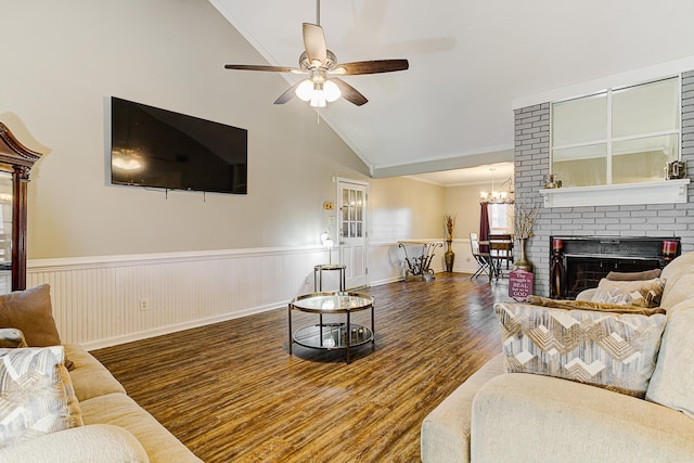 living room featuring lofted ceiling, ceiling fan with notable chandelier, a brick fireplace, dark hardwood / wood-style floors, and ornamental molding