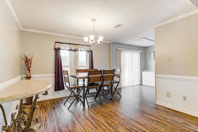 dining room featuring crown molding, dark hardwood / wood-style flooring, a textured ceiling, and a notable chandelier