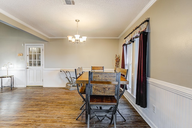 dining room with a textured ceiling, a notable chandelier, wood-type flooring, and ornamental molding