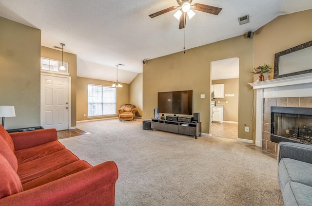 carpeted living room with a tile fireplace, a textured ceiling, ceiling fan with notable chandelier, and high vaulted ceiling