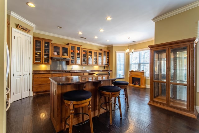 bar featuring dark hardwood / wood-style flooring, stainless steel gas stovetop, crown molding, sink, and hanging light fixtures