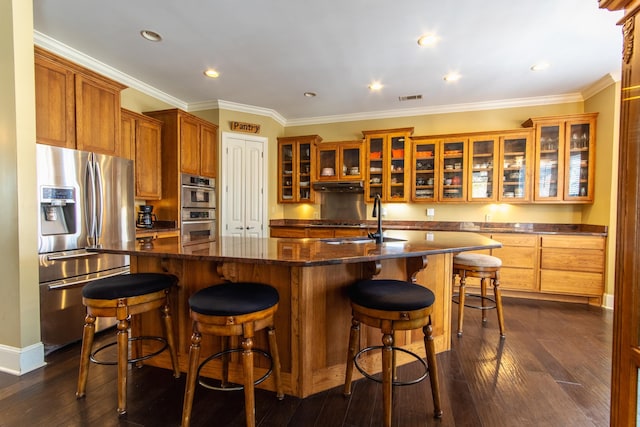 kitchen featuring a kitchen island with sink, sink, crown molding, dark hardwood / wood-style floors, and appliances with stainless steel finishes