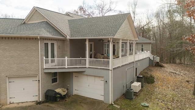 back of property with covered porch, central AC, and a garage