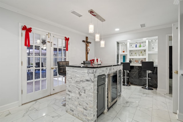 kitchen with built in shelves, decorative light fixtures, a kitchen island, and crown molding