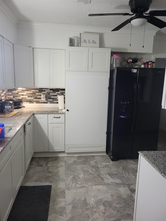 kitchen with black refrigerator with ice dispenser, light stone counters, a textured ceiling, ceiling fan, and white cabinets