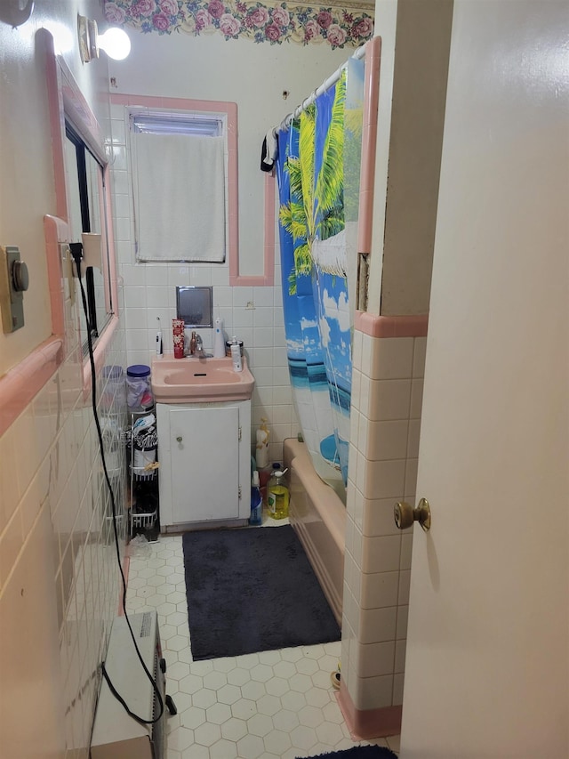 bathroom featuring shower / bathtub combination with curtain, tile patterned flooring, vanity, and tile walls