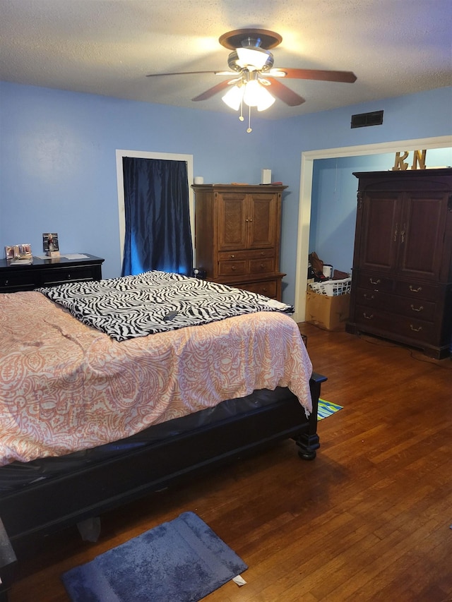 bedroom featuring a textured ceiling, dark hardwood / wood-style flooring, and ceiling fan