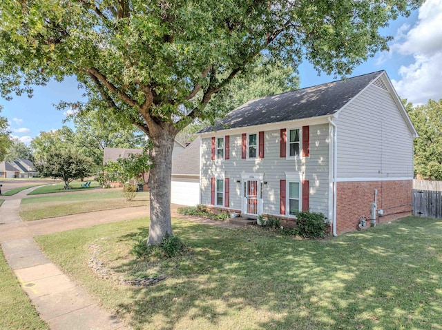 colonial-style house featuring a garage and a front lawn