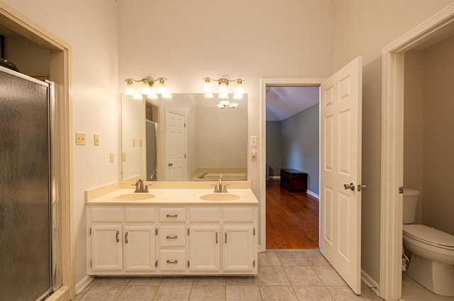 bathroom featuring tile patterned flooring, vanity, an enclosed shower, and toilet