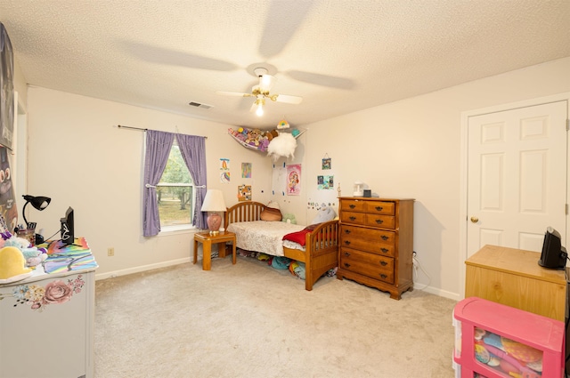 bedroom featuring ceiling fan, light colored carpet, and a textured ceiling