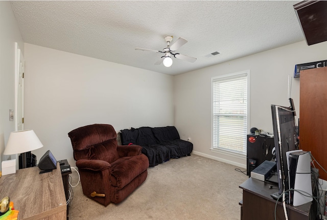 living area featuring ceiling fan, light carpet, and a textured ceiling