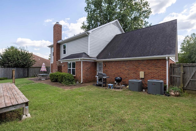 rear view of house with cooling unit, a yard, and a patio area