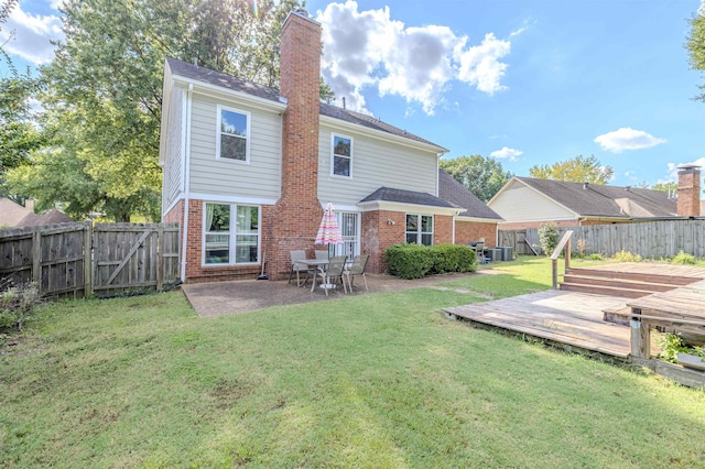 back of property with a wooden deck, a lawn, and a patio area