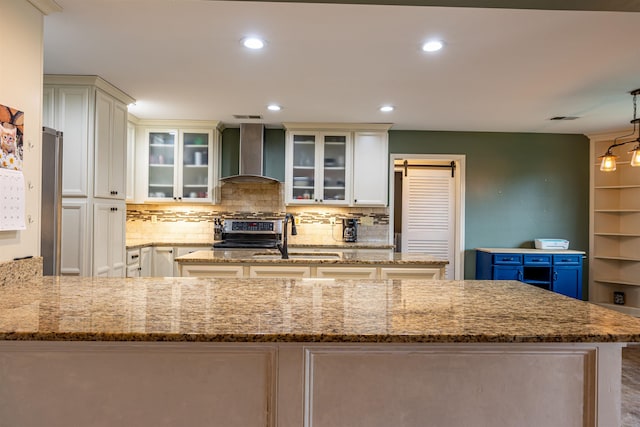 kitchen with decorative light fixtures, sink, electric range, light stone countertops, and wall chimney range hood