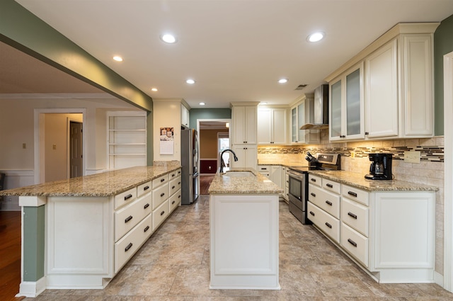 kitchen featuring wall chimney exhaust hood, appliances with stainless steel finishes, sink, and a center island with sink