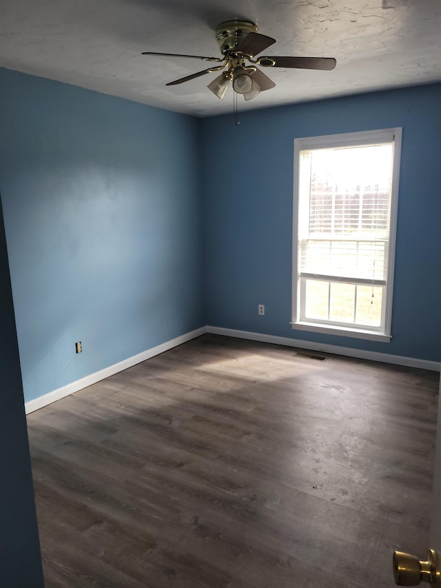 spare room with dark wood-type flooring and ceiling fan