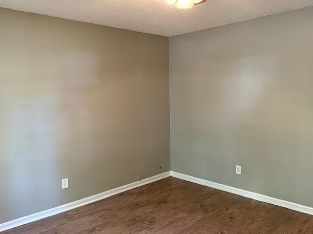 empty room featuring dark hardwood / wood-style flooring and a textured ceiling