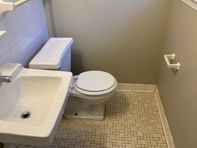 bathroom featuring tile patterned floors, toilet, tile walls, and sink