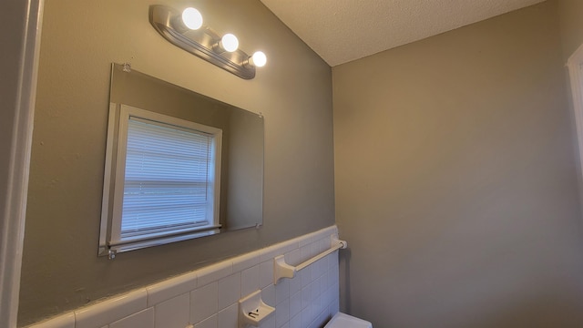 bathroom with a textured ceiling and tile walls