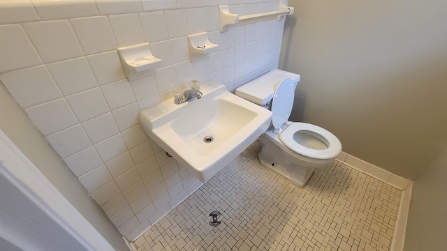 bathroom with tile patterned flooring, toilet, tile walls, and sink