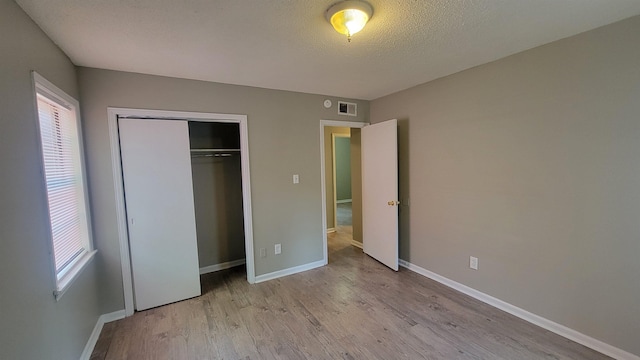 unfurnished bedroom with light hardwood / wood-style floors, a textured ceiling, and a closet