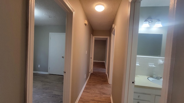 corridor with hardwood / wood-style floors and a textured ceiling