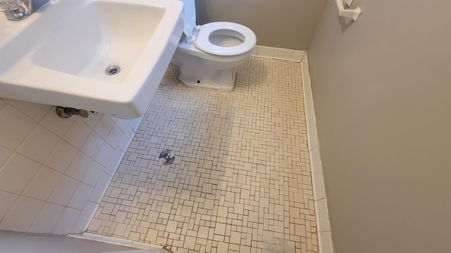 bathroom featuring tile patterned flooring, a shower, toilet, and sink