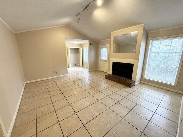 unfurnished living room featuring lofted ceiling, a healthy amount of sunlight, track lighting, and a brick fireplace