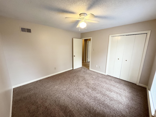 unfurnished bedroom with carpet flooring, ceiling fan, a closet, and a textured ceiling