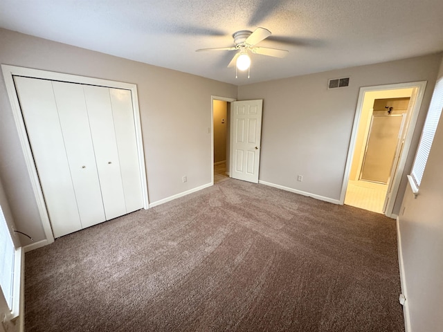 unfurnished bedroom featuring ceiling fan, dark carpet, and a textured ceiling