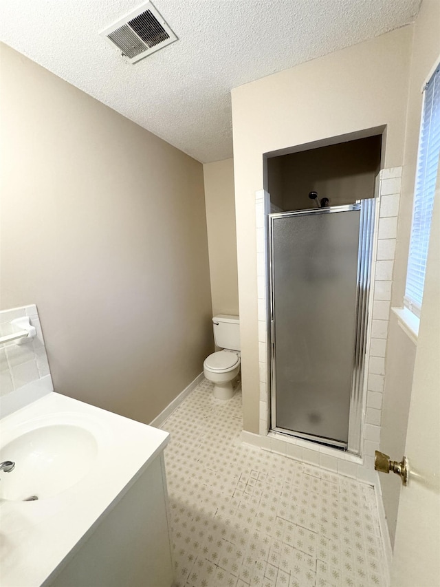 bathroom featuring vanity, a shower with shower door, a textured ceiling, and toilet