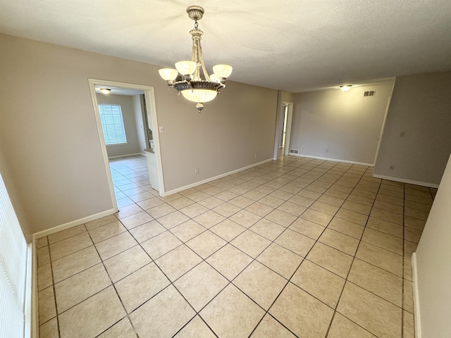 unfurnished room featuring light tile patterned floors, a textured ceiling, and a notable chandelier