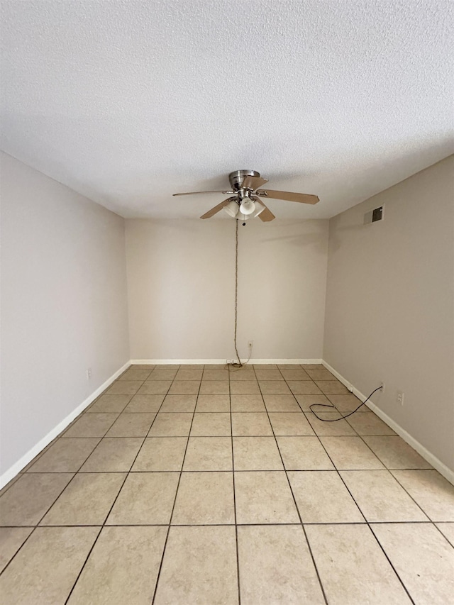 spare room with ceiling fan, light tile patterned floors, and a textured ceiling