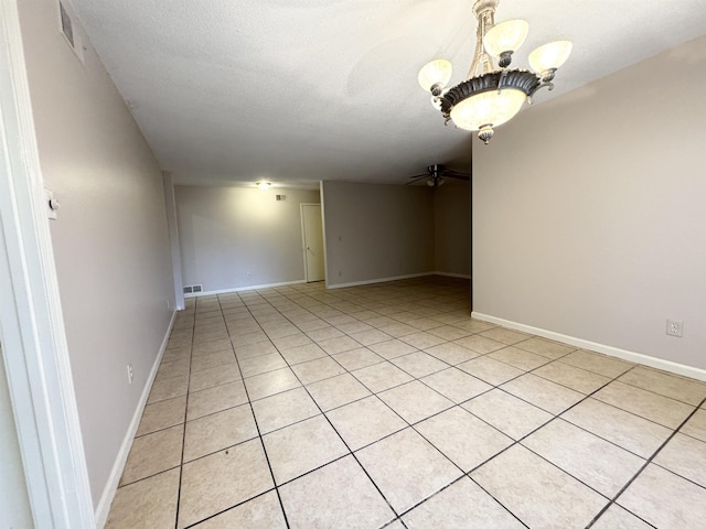 unfurnished room featuring a textured ceiling, light tile patterned floors, and ceiling fan with notable chandelier