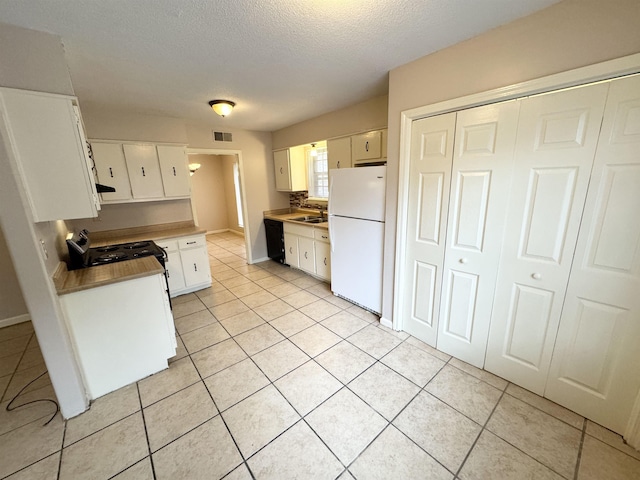 kitchen with dishwasher, light tile patterned flooring, white fridge, a textured ceiling, and white cabinets