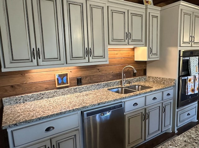 kitchen featuring wooden walls, sink, stainless steel appliances, and stone countertops