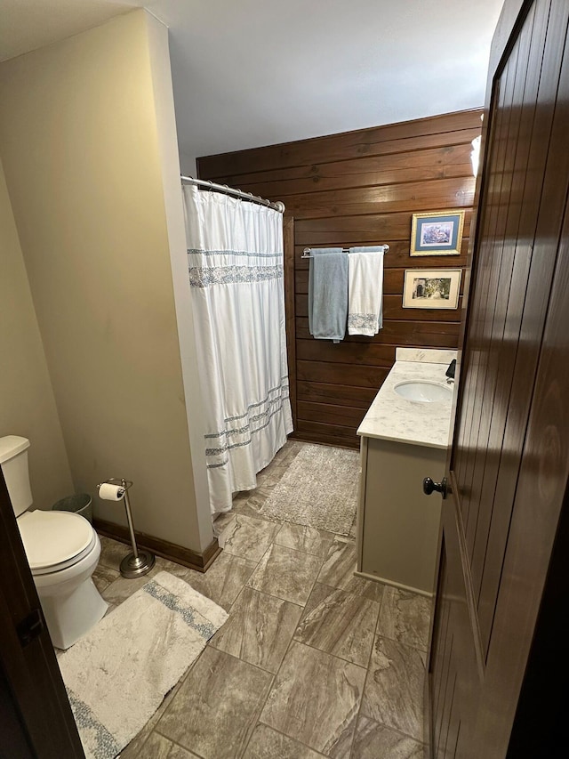 bathroom featuring wooden walls, vanity, and toilet