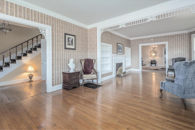 sitting room with wood-type flooring, built in features, and ornamental molding