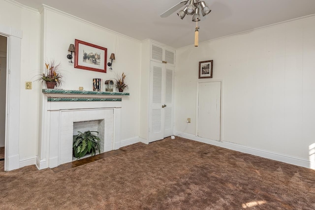 unfurnished living room with a brick fireplace, ceiling fan, dark carpet, and ornamental molding