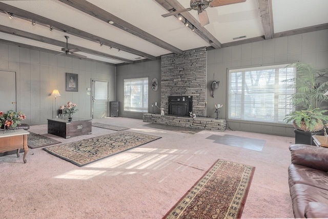 carpeted living room with ceiling fan, a fireplace, beamed ceiling, and rail lighting