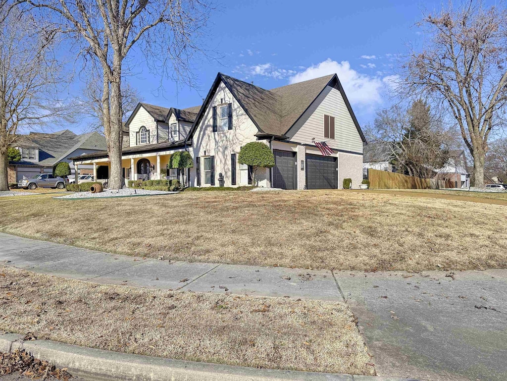 view of front of property with covered porch, a garage, and a front lawn